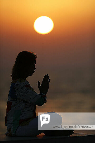 Woman practising yoga pose and meditation at sunset as concept for silence and relaxation  United Arab Emirates  Middle East