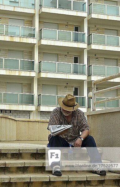 Mann mit Hut liest Zeitung auf Treppe vor Hochhaus  Villaricos  Andalusien  Spanien  Europa