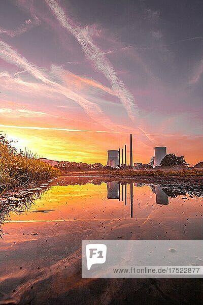 Schöner Sonnenaufgang in einem Feld  mit einer Pfütze im Sonnenaufgang. Gegenlicht Aufnahme am Morgen  im Hintergrund das Kohlekraftwerke Staudinger  Hainburg  Hessen  Deutschland  Europa