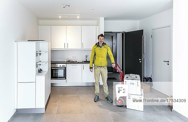 Young man with moving boxes  standing in modern kitchen of a flat  moving to a new flat  Munich  Bavaria  Germany  Europe