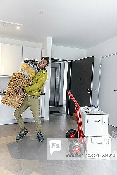 Young man carrying heavy moving boxes  standing in modern kitchen of a flat  moving to a new flat  Munich  Bavaria  Germany  Europe