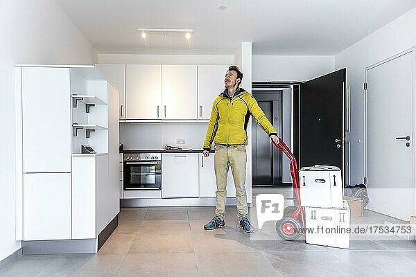Young man with moving boxes  standing in modern kitchen of a flat  moving to a new flat  Munich  Bavaria  Germany  Europe