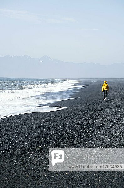 Woman walking on a black sand beach  Reynisfjara beach  South Iceland  Iceland  Europe