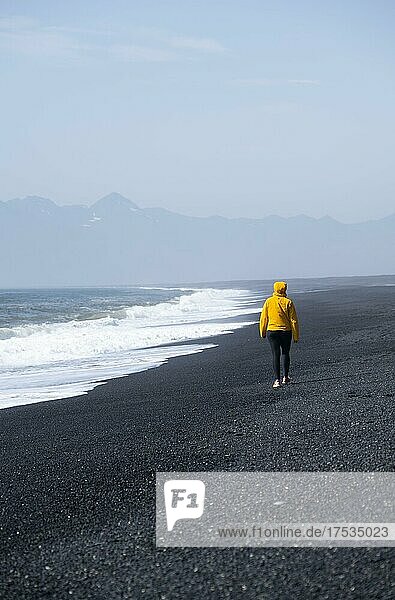 Frau geht an einem Schwarzen Sandstrand  Reynisfjara Strand  Südisland  Island  Europa