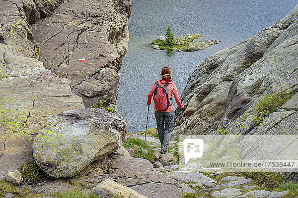 Woman with backpack and hiking poles walking towards Lac Fourca lake  Maritime Alps  Mercantour National Park  France