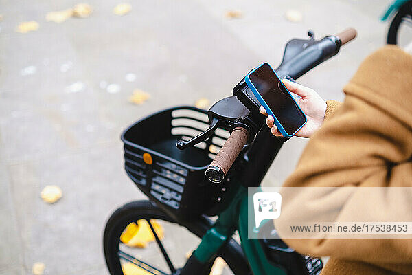 Woman using smart phone to rent electric bicycle