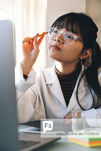 Young scientist wearing eyeglasses contemplating in laboratory