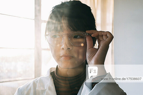 Young scientist wearing eyeglasses looking away in laboratory