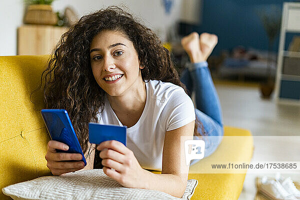 Young woman doing online payment through credit card at home
