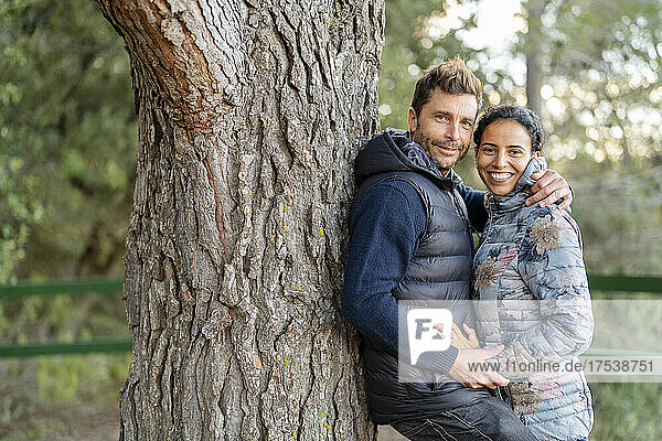 Man leaning on tree embracing woman at park