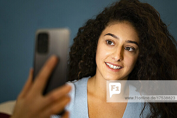 Woman taking selfie through smart phone in bedroom