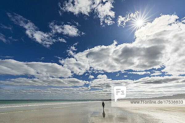 Australia  South Australia  Robe  Summer clouds over silhouette of female tourist walking alone along Fox Beach