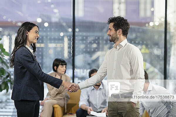 Smiling businesswoman handshaking colleague in office