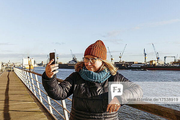 Senior woman taking selfie through smart phone at harbor
