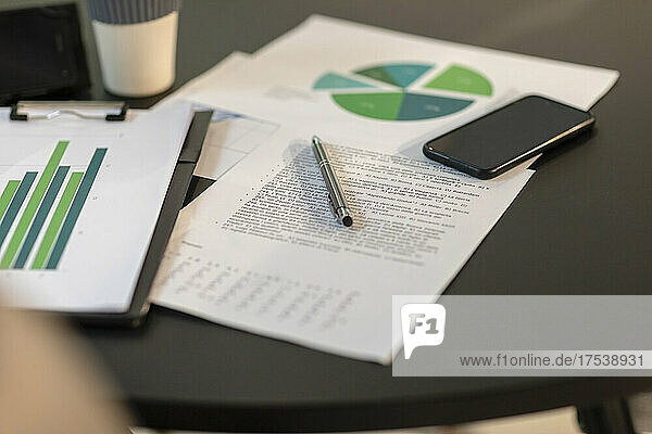 Paper documents and smart phone on table at office