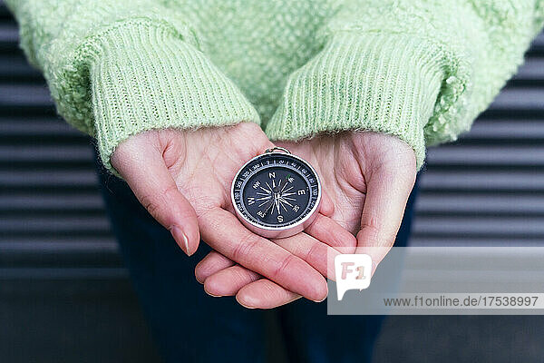 Woman holding navigational compass on palm
