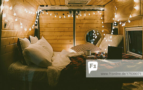 Laptop on bed in illuminated camper van