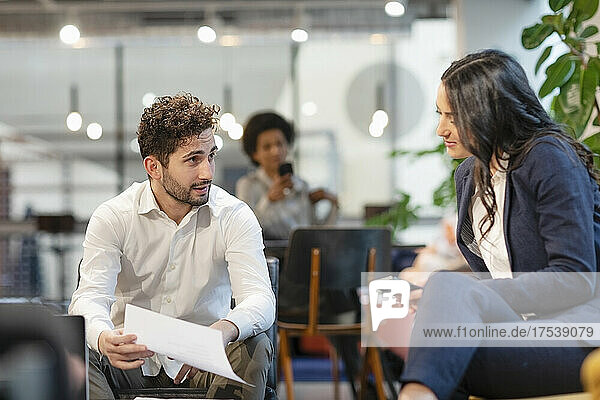 Businessman discussing document with colleague at office