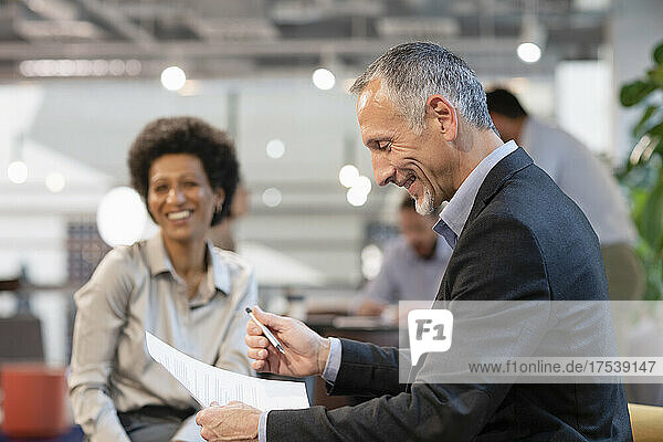 Smiling businessman discussing with colleague in office