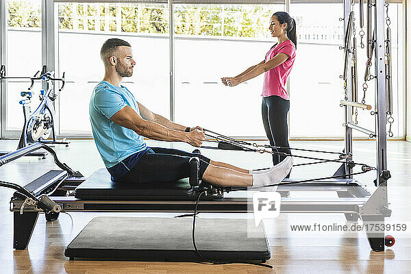 Fitness instructor showing exercise to athlete on exercise equipment