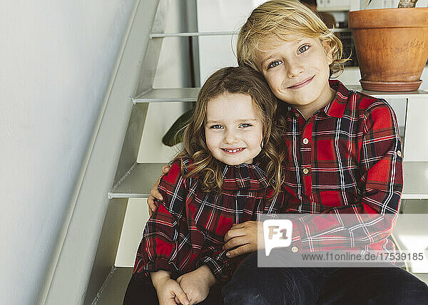 Smiling brother and sister sitting together on staircase