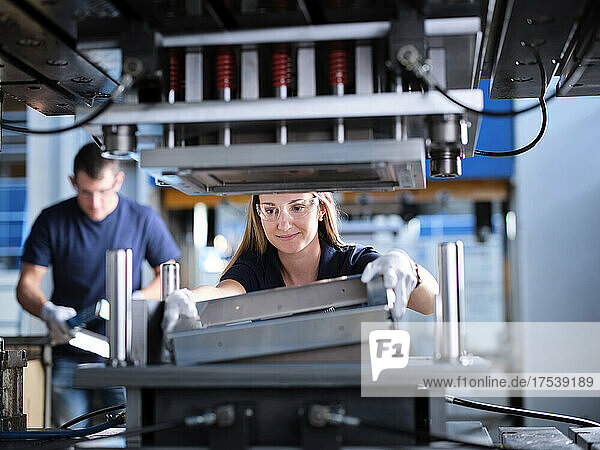 Engineer adjusting metal frames in machine at factory