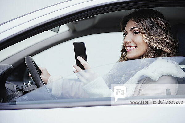 Woman using mobile phone in car