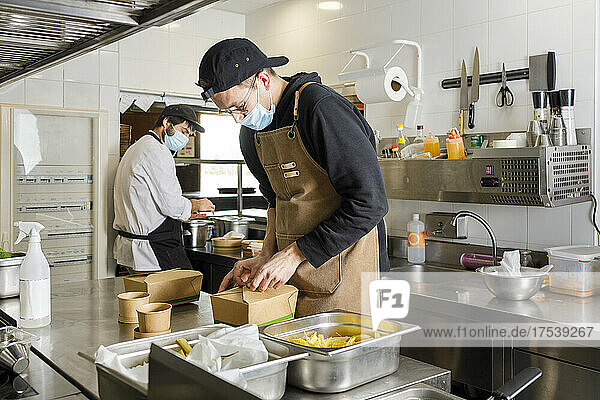 Chefs preparing takeaway food in kitchen at restaurant