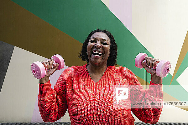 Cheerful woman exercising with pink dumbbells