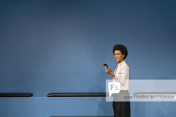 Smiling businesswoman using mobile phone at workplace