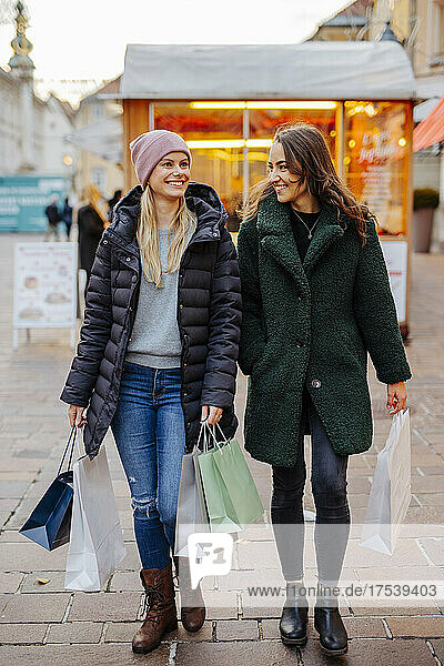 Women wearing warm clothing walking with shopping bags in market