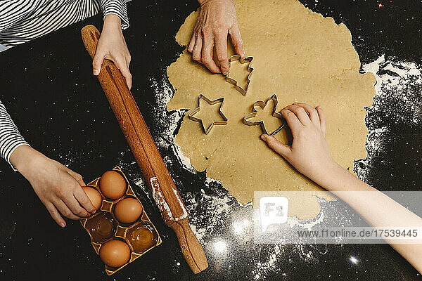 Family preparing cookies with cookie cutter on kitchen island