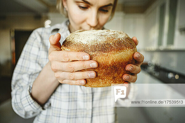 Woman smelling fresh bread in kitchen at home