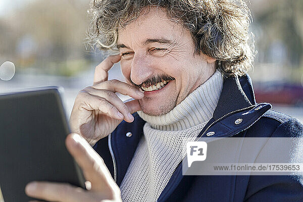 Happy man using tablet PC on sunny day