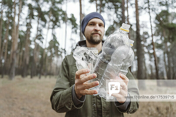 Man holding plastic water bottles in forest
