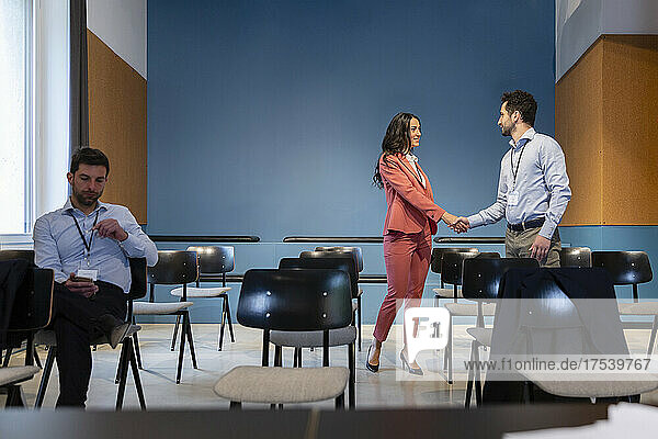 Businesswoman shaking hand with businessman at conference