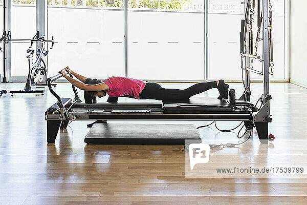 Sportswoman lying and exercising on equipment at gym
