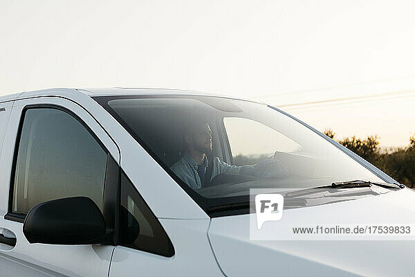 Delivery man in white van at sunset