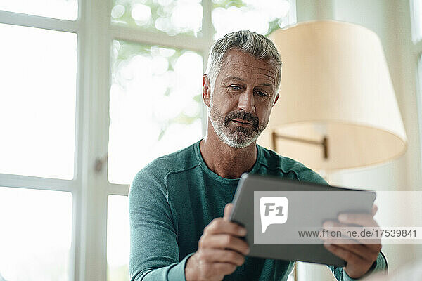 Mature man using tablet PC at home