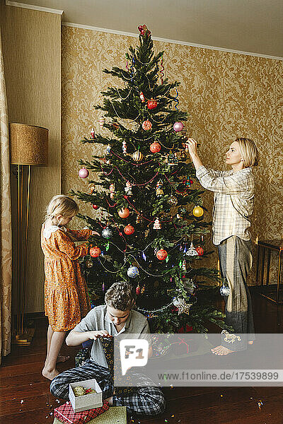 Family decorating christmas tree at home