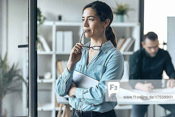 Contemplative businesswoman with eyeglasses in small office