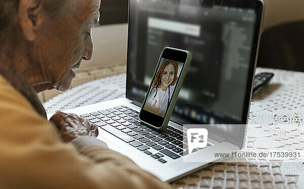 Senior woman consulting doctor on video call through smart phone at home