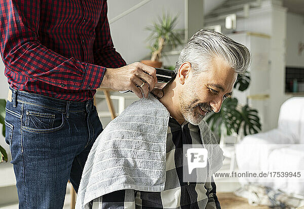 Husband cutting husband's hair with electric razor at home