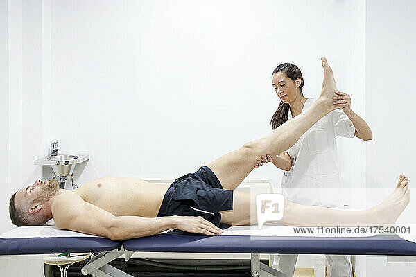 Physical therapist stretching athlete's leg on massage table