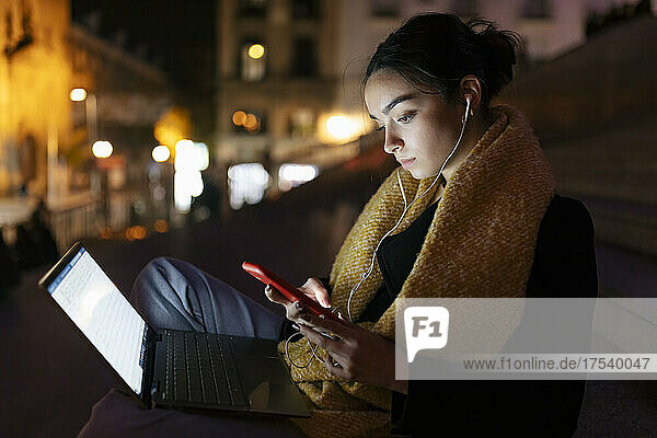 Teenage girl with laptop listening music through earphones