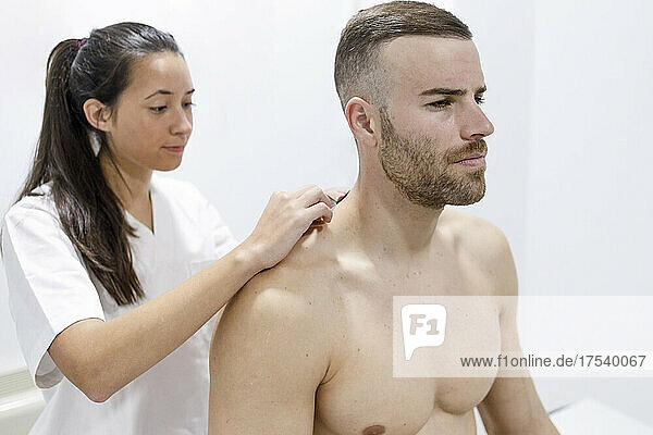 Physical therapist putting tape on shirtless athlete