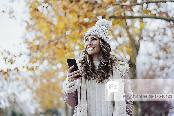 Happy woman holding smart phone at park
