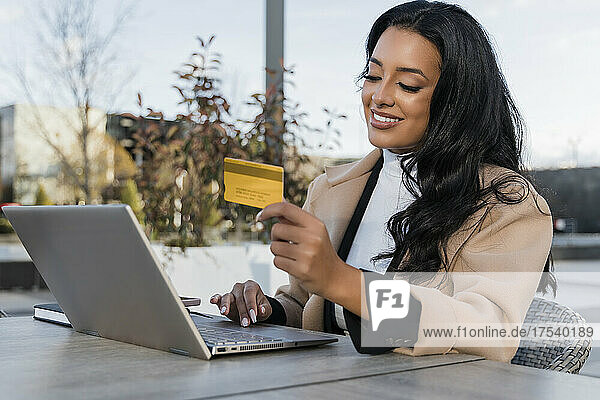 Smiling businesswoman with credit card doing online shopping on laptop