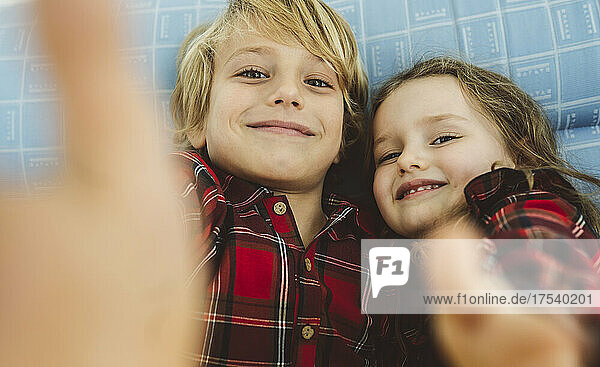 Smiling boy and girl taking selfie at home
