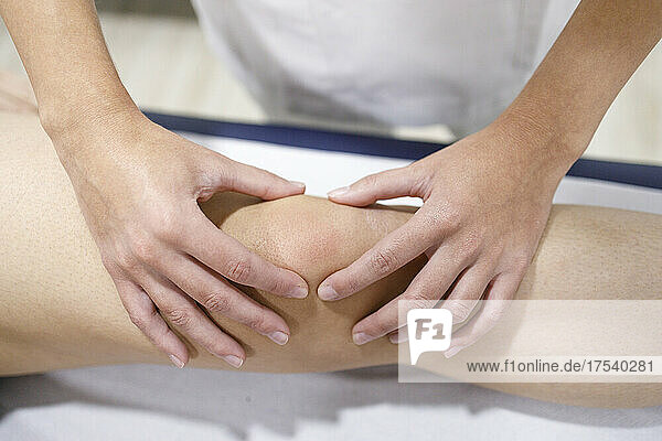 Physical therapist massaging athlete's leg on massage table